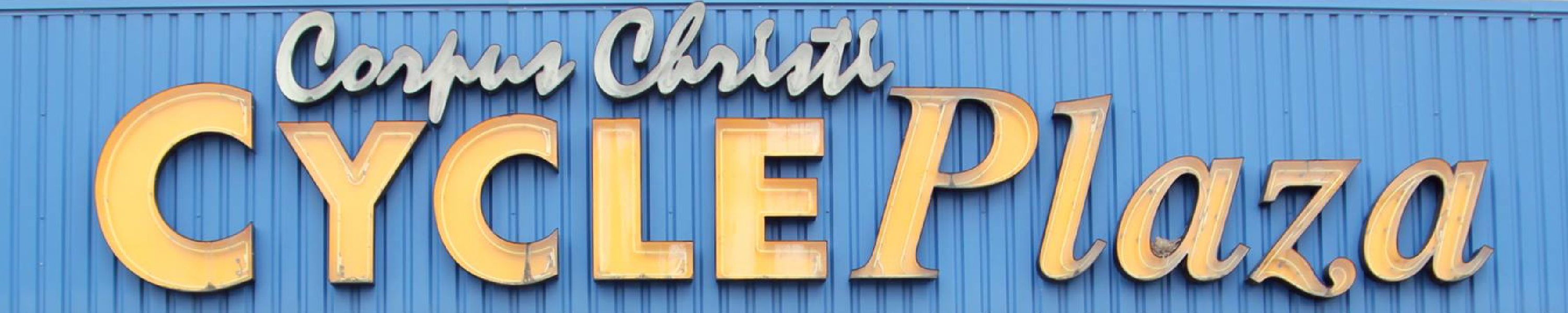 Close-up of person wearing jeans on a dark red Indian Motorcycle® overlooking an empty grassy field.