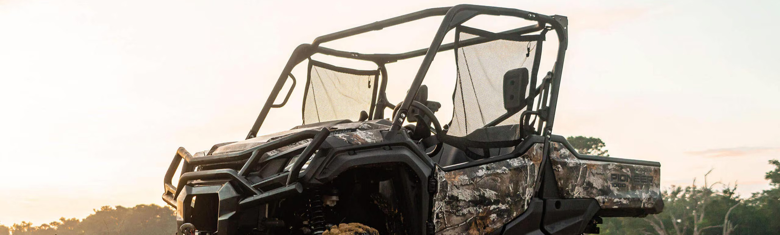 camo honda pioneer parked in an open field