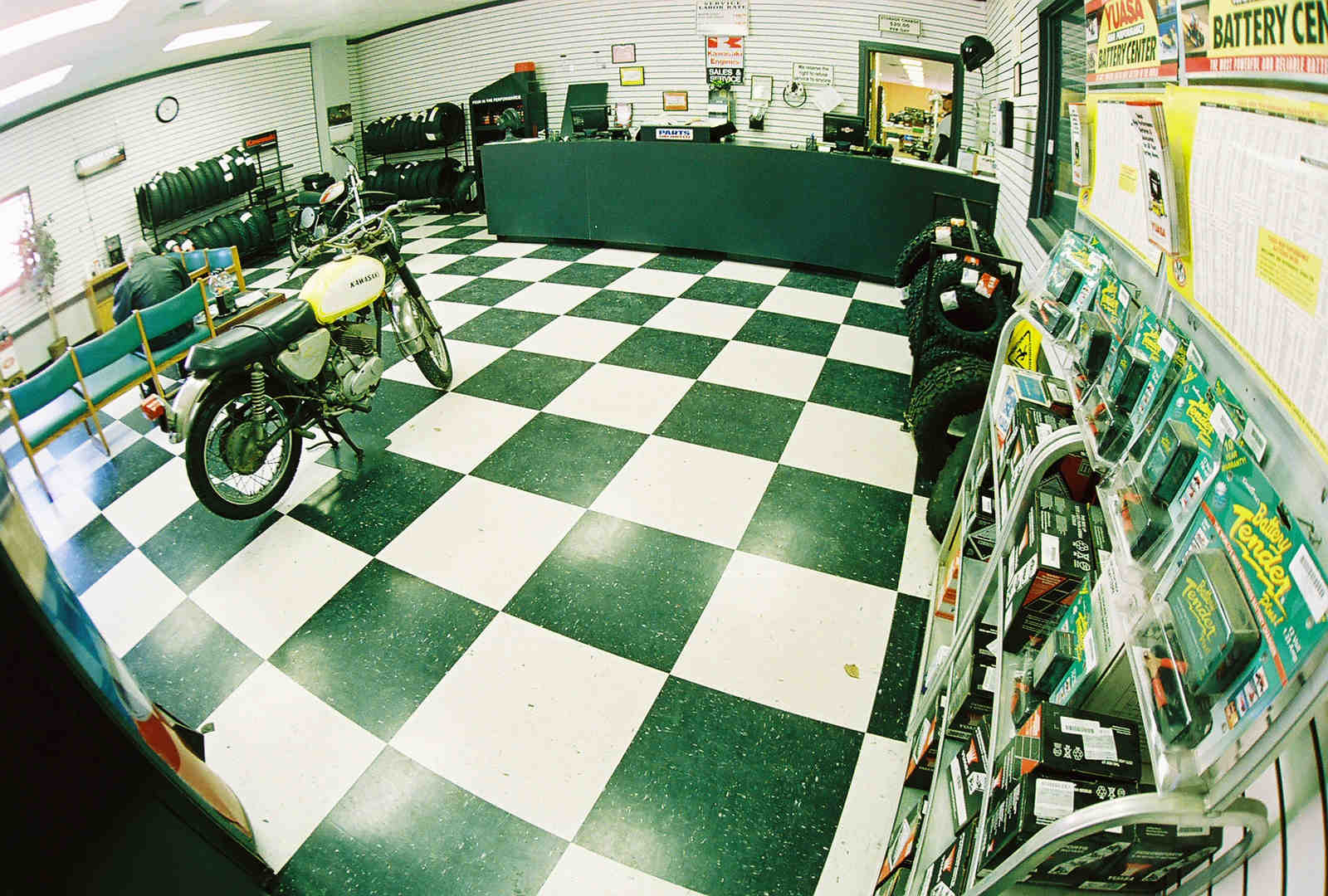 A black motorcycle parked in a service room with a black & white checkerboard pattern floor.