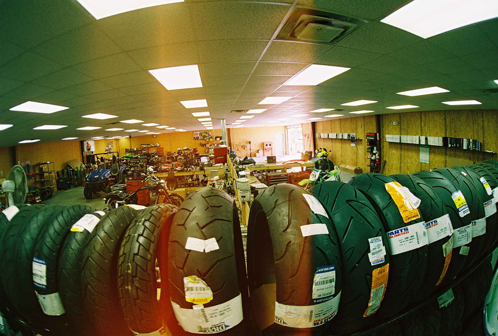Row of powersports tired inside a workshop with an open door in the back right of the room.